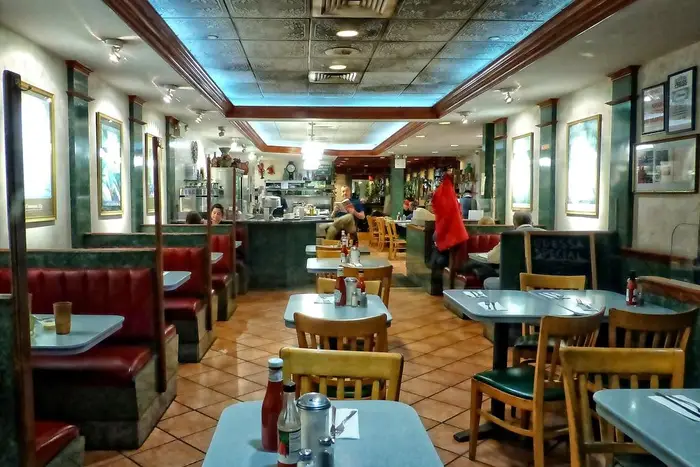 The interior of Odessa diner, showing tables in the middle and booths on the sides, with a counter in the back.